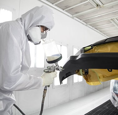 Car parts being painted by service technician
